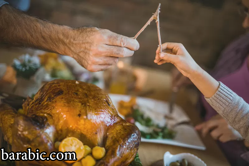 رجل وطفل لا يمكن التعرف عليهما يسحبان عظم الترقوة في عشاء عيد الشكر