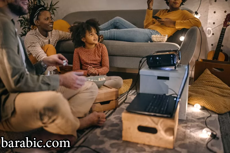 عائلة تجلس معا تشاهد الأفلام على شاشة جهاز العرض