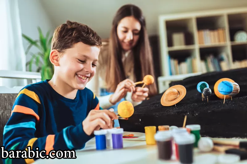 صبي وفتاة مدرسة سعيدة يصنعان نظاما شمسيا