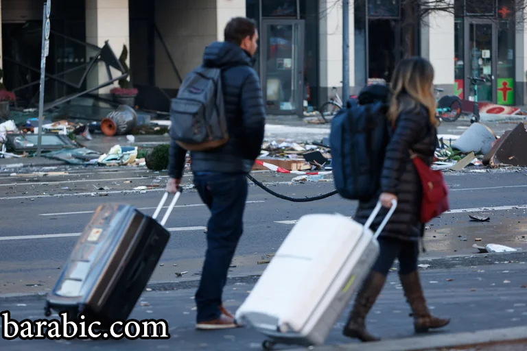 يغادر الضيوف الفندق سيرا على الأقدام بجانب الأنقاض في الشارع بعد انفجار ويهربون من أكوادوم أكواريوم