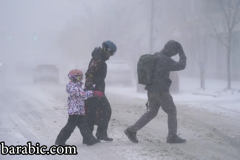 عائلة فايرستون تعبر شارع إلموود في بوفالو ، نيويورك ، تحت العاصفة الثلجية